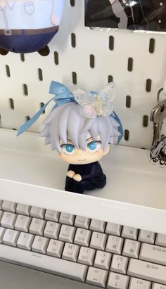 a small doll sitting on top of a keyboard