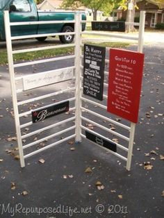 a metal gate with signs on it in front of a green truck and some trees