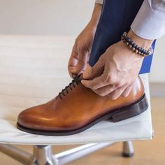 a man is tying his shoes on a chair