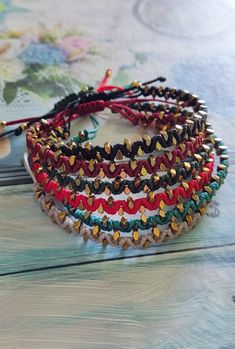 a stack of bracelets sitting on top of a wooden table next to a book