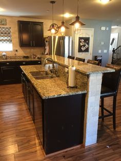 a large kitchen with an island in the middle and two lights hanging from the ceiling