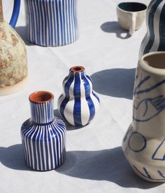 blue and white striped vases sitting on top of a cloth covered table next to each other