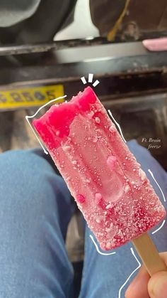 a popsicle is being held up to show the pink substance on it's side