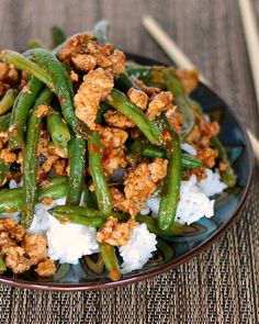 a plate with green beans, rice and meat on it next to chopsticks