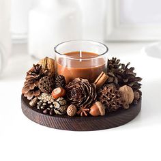 a candle that is sitting on top of a wooden stand with pine cones and nuts