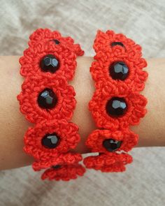 two red crocheted bracelets with black beads on someone's arm,