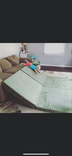 a little boy laying on top of a large green mattress in the middle of a living room