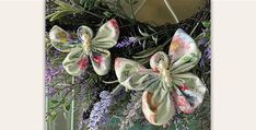 a wreath with flowers and ribbons hanging from it