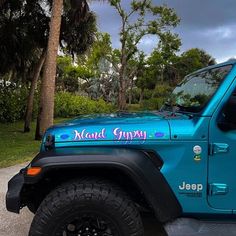 a blue jeep is parked on the side of the road in front of some trees