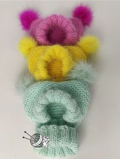 three knitted hats with pom - poms on top and one in the middle