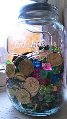 a jar filled with lots of coins sitting on top of a table