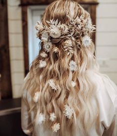 the back of a woman's head with long hair and flowers in her hair