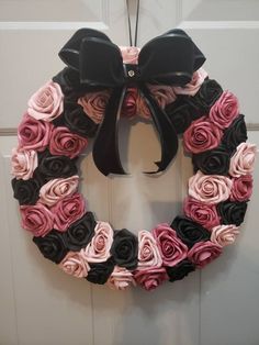 a pink and black wreath hanging on a door