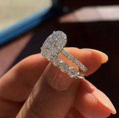 a close up of a person's hand holding a ring with two diamonds on it