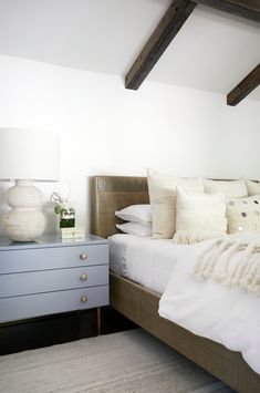 a bed with white sheets and pillows on top of it next to a night stand