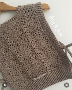 a crocheted apron hanging on a wooden hanger