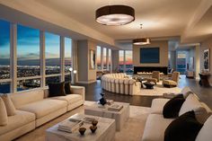 a living room filled with white couches and large windows overlooking the city at night