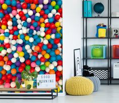 a room filled with lots of different colored balls on the wall next to a book shelf