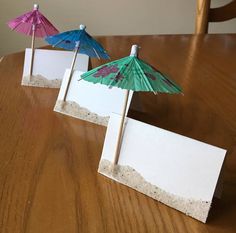 three paper umbrellas sitting on top of a wooden table