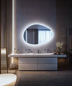 a bathroom with a round mirror and lights on the wall above it, along with two sinks