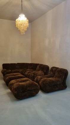 a large sectional couch sitting on top of a white floor next to a chandelier