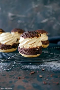 three chocolate cookies with cream frosting on a cooling rack