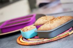 two loafs of bread sitting on top of a plate next to some colorful bowls