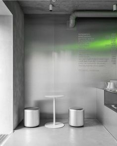 a white table and two stools in a room with green lights on the wall