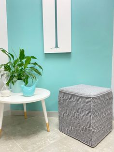 a table with a potted plant on it next to a white stool and blue wall