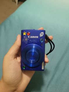 a person holding a camera in their left hand on a blue surface with other items