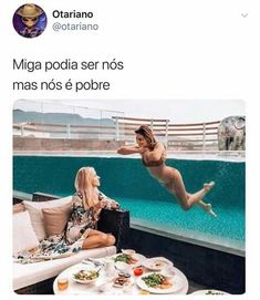 two women sitting on couches in front of a swimming pool and one is jumping into the water