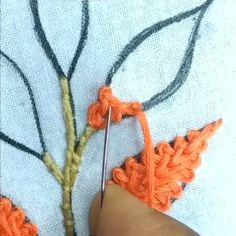 someone is crocheting an orange piece of fabric