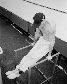 a man sitting on top of a metal rail next to a white trailer behind him