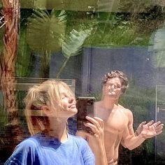 two people standing in front of a mirror with their hands out and one person looking up