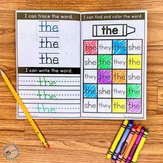 an open book with colorful crayons and pencils next to it on a wooden table