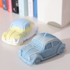 two toy cars sitting next to each other on a white counter top in front of bookshelves