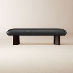 a black bench sitting on top of a white floor next to a beige wall with no one around it