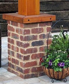 two planters with flowers in them sitting next to a brick pillar on the sidewalk