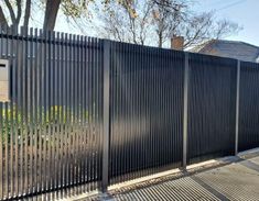 a black fence with a sign on it next to some trees and houses in the background