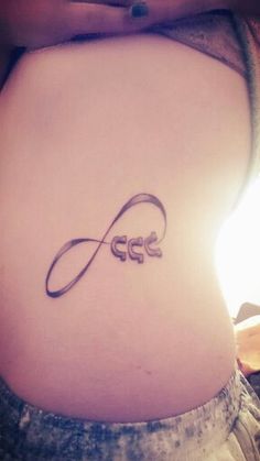 a woman's stomach with an infinite symbol tattoo on her lower back and the word love written in cursive writing