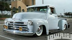 an old blue truck parked in front of a building