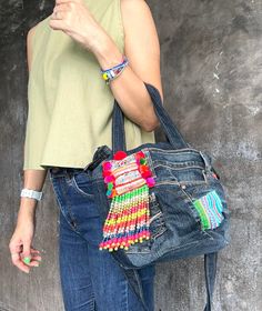 a woman is holding a purse made out of old jeans and beaded bracelets