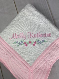 a pink and white quilted blanket with personalized name on it