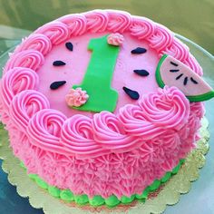 a pink cake with green icing and a number one on it's top