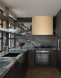 a modern kitchen with marble counter tops and wooden cabinets, along with stainless steel appliances