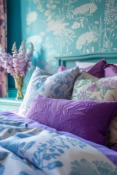 a bed with purple and blue pillows on top of it in front of a green wall