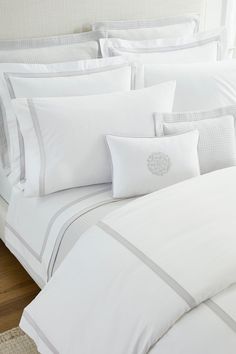 a bed with white sheets and pillows on top of it