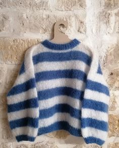 a blue and white striped sweater hanging on a brick wall