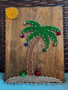 a string art palm tree on a wooden board with bead work and beads around it