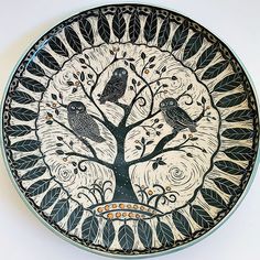 a decorative plate with two birds sitting on a tree in front of the moon and stars